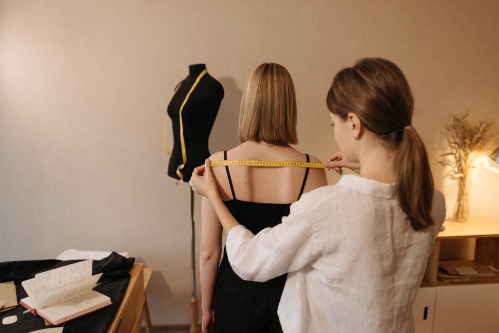 An image of a tailor measuring a woman to fit a garment